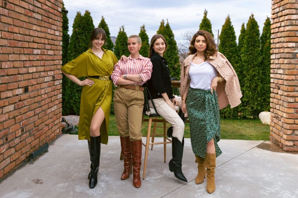 Four women showcasing unique outfits and boots, posing confidently outdoors.