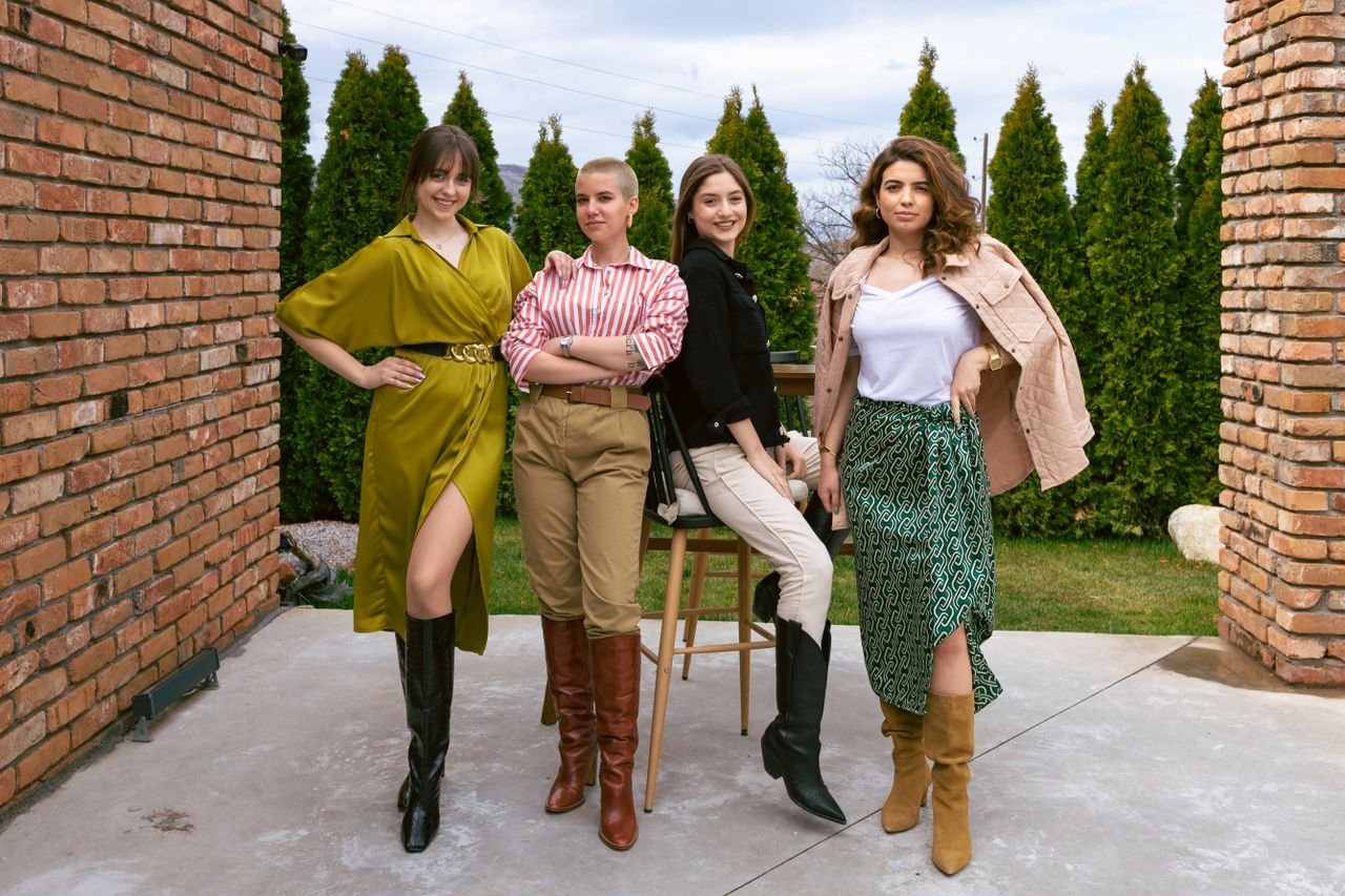 Four women showcasing unique outfits and boots, posing confidently outdoors.