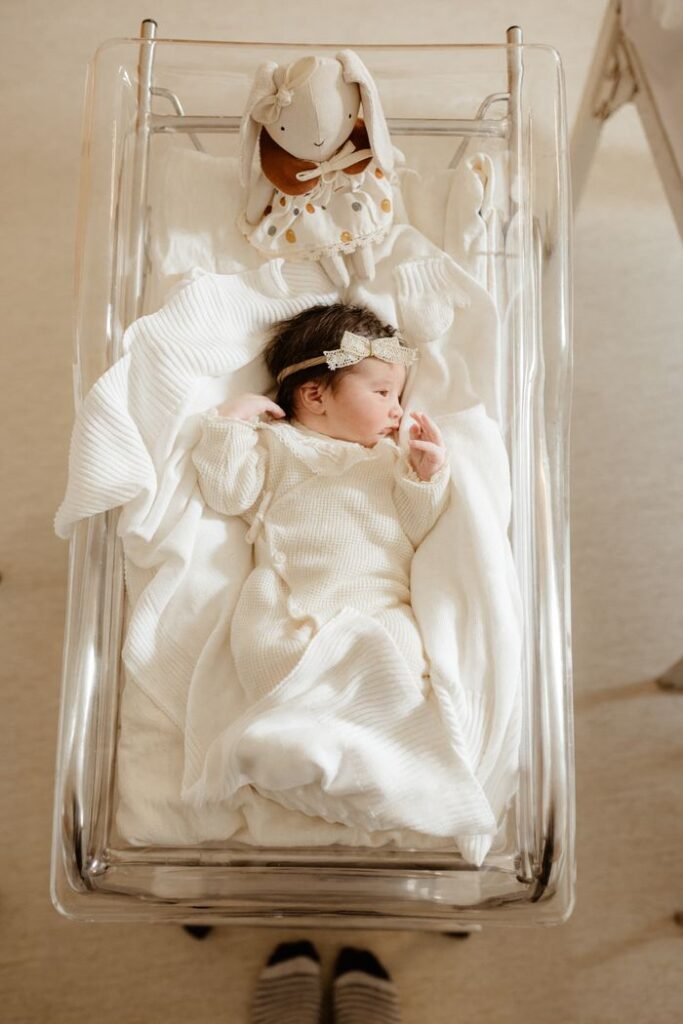 Adorable newborn baby girl lying in a hospital bassinet with a bunny toy, captured in a serene setting.