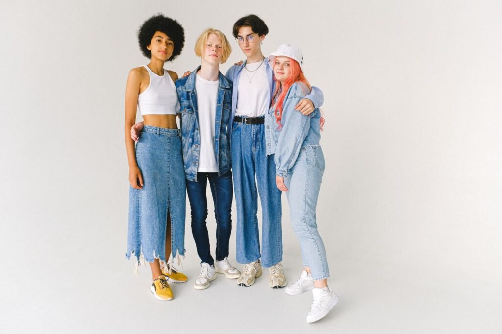 Full length of confident multiracial friends in casual clothes standing in studio while hugging on white background while looking at camera
